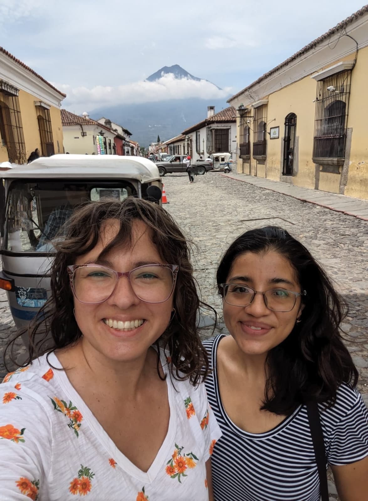 Spanish teacher and student exploring cobblestone streets in Antigua Guatemala with volcano view