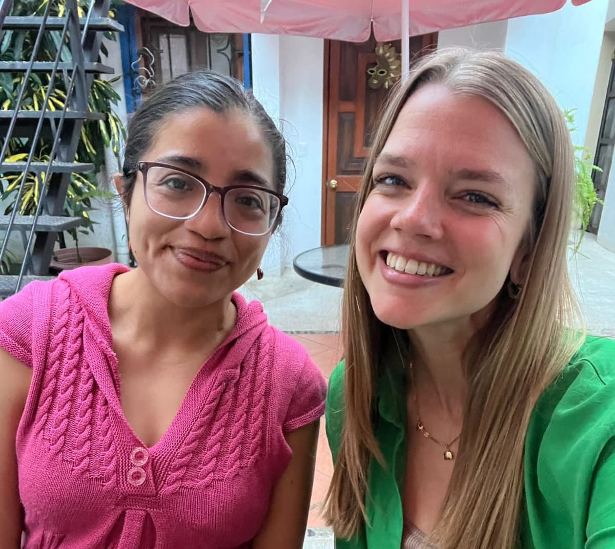 Spanish teacher and student smiling together at a courtyard cafe in Oaxaca