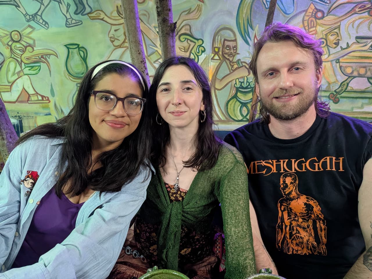 Spanish teacher and students at a colorful pulque bar with mural-covered walls in Oaxaca