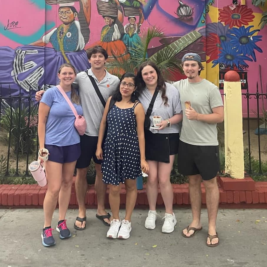 Spanish teacher and students enjoying ice cream in front of a colorful street mural in Oaxaca